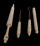 Lote contendo quatro pequenas peças em marfim, sendo um fuso, um estilete, um gancho e um cilindro torneado, com elementos metálicos em duas das peças. Medidas: 10 cm, 7,2 cm, 8 cm e 8 cm.
