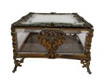 Antiga caixa francesa porta-joias, com estrutura em vidro bisotado e guarnições em metal ricamente trabalhado em relevo.Tampa articulada com moldura ornamentada, laterais envidraçadas e apoiada sobre pés vazados. Medidas: 13 x 20 x 20 cm.