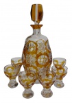 Conjunto Art Déco em cristal, composto por garrafa licoreira e seis copinhos, em tonalidade âmbar double, ricamente lapidados com motivos geométricos e estrelas. Garrafa com tampa original facetada e copinhos com base moldada. Medidas: garrafa 27 x 12 cm; copinhos 7 x 5 cm