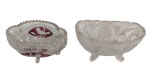 Duas cestas em cristal, ambas apoiadas sobre pés moldados. Uma de formato oval, ricamente lapidada em padrões geométricos, e outra circular, com lapidação e aplicação em cristal double na tonalidade rubi, decorada com motivos de pássaros. Medidas: 7,4 x 15 x 9 cm; 6,5 x 12,5 x 9 cm.