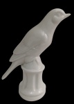 Escultura de pássaro em porcelana branca, representando ave pousada sobre base moldurada. Medidas: 18 x 6 cm.