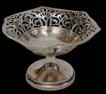 Antiga uveira em metal espessurado a prata, marcada, com corpo elevado sobre pedestal e borda vazada ornamentada por motivos florais estilizados, em estilo Art Nouveau. Medidas: 7 x 10,4 cm.