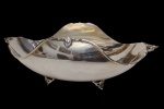 Antiga e imponente fruteira em metal espessurado a prata, marcada na base, com corpo de contorno ondulado, apoiada sobre quatro pés ornamentados e aplicações em relevo nas bordas, no estilo Art Nouveau. Medidas: 9,5 x 28 x 14,3 cm.