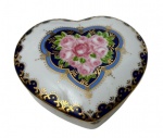 Italy Style, caixa em porcelana esmaltada e vitrificada, em formato de coração, decoração floral de rosas policromadas em reserva sobre fundo branco, bordas em azul cobalto e rica ornamentação dourada. Manufatura na base. Medidas: 4 x 10 x 9,5 cm.