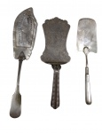 Três utensílios de servir em metal espessurado a prata, composto por espátula vazada para servir, pá para torta ricamente gravada e espátula para servir. Medidas: 31 / 26 / 24,5 cm.