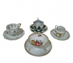 Quatro xícaras de coleção para café em porcelana, de manufaturas e modelos distintos, com decorações florais em policromia, relevos moldados e detalhes em douração.