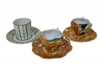 Três xícaras de coleção para café em porcelana, de modelos distintos, com decorações em relevo, policromia e detalhes em ouro.