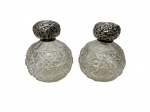 Par de antigos perfumeiros de época vitoriana/eduardiana com corpos esféricos em cristal translúcido, ricamente decorados com lapidação profunda em padrão "bico de jaca" e geométrico, encimados por suntuosas tampas bulbosas em prata de lei profusamente cinzeladas à mão com motivos florais, volutas e ramagens em relevo. Medidas: 9 x 10,5 cm. Uma das peças apresenta quebrado no gargalo de cristal.