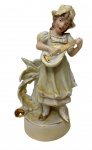 Antiga escultura em porcelana biscuit com acabamento acetinado e detalhes ricamente decorados com pintura em tons pastéis, representando uma jovem musicista com trajes românticos de época e chapéu. Medidas:17,5 x 9 cm.