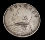 China. Moeda de 1 Yuan ("Dollar de Yuan Shikai"), em prata, apresentando no anverso o busto de Yuan Shikai com inscrições em caracteres chineses e, no reverso, o valor facial "" (1 Yuan) envolto por coroa de ramos. Exemplar de expressivo interesse histórico e numismático. Peso: 26,6 g. Medidas: 3,9 cm.