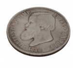Brasil Império. Moeda de 2.000 Réis, 1888, em prata, ostentando no anverso o busto de D. Pedro II, circundado pela legenda imperial e data. No reverso, brasão do Império do Brasil coroado, ladeado por ramos de café e tabaco, com a inscrição "Decreto de 1870" e valor facial 2.000 Réis. Exemplar de grande interesse histórico e numismático, pertencente à última série monetária de prata do período imperial brasileiro. Peso: 25,4 g. Medidas: 3,7 cm de diâmetro.
