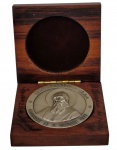 Antiga medalha comemorativa prateada de São Charbel (Saint Charbel), acondicionada em estojo de madeira. Anverso com busto em relevo de São Charbel Makhlouf, circundado pelas inscrições em francês e árabe "Canonisé le 9 Octobre 1977". Reverso com representação do Cedro do Líbano em relevo, acompanhado de inscrições em latim e árabe alusivas ao santo e ao Líbano. Peso: 60,2 g. Medidas: 5 cm de diâmetro.