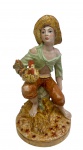SUREDA, Espanha. Antiga e imponente escultura em porcelana esmaltada e policromada, representando jovem camponês sentado sobre feixe de feno, segurando um galo, com base em relevo simulando vegetação.  Manufatura  na base. Medidas: 33,5 x 18,5 cm.