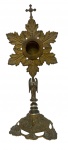 Arte Sacra - Antigo relicário em bronze e metal, ornamentado por folhagens, perolados e cachos de uva em relevo, com haste representando anjo e remate superior em forma de cruz. Medidas: 18 x 11,5 x 11 cm.