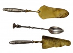Três peças de servir, sendo duas espátulas para bolo em metal espessurado a prata com lâminas em vermeil e uma colher de servir, todas com cabos ricamente cinzelados em relevo de motivos florais e vegetalistas. Medidas: 27 cm, 20 cm e 24 cm.
