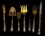 PRATA. Sete talheres de servir, com cabos em prata de lei, sendo garfos, espátulas, faca para peixe, faca para queijo e utensílio de serviço, alguns com partes funcionais em vermeil. Cabos ricamente ornamentados em relevo, com decoração de inspiração floral e rocaille. Medidas: 25,5 cm, 25 cm, 30 cm, 26 cm, 24 cm, 18 cm e 17 cm.