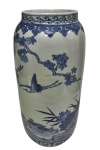 Antigo e imponente vaso em porcelana, de formato cilíndrico, esmaltado e decorado em azul sobre fundo branco, representando paisagem oriental com garças em voo, vegetação e elementos naturais. Borda ornamentada por frisos de inspiração oriental. Medidas: 41,5 x 19 cm.