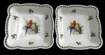 Schumann Bavaria - Par de travessas quadradas em porcelana alemã vazada, esmaltadas e policromadas, decoradas ao centro com motivo de araras e delicados arranjos florais. Bordas recortadas e vazadas, com manufatura na base. Medidas: 21,5 x 21 cm.