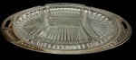 Petisqueira em metal espessurado a prata, composta por bandeja oval com alças vazadas e quatro recipientes removíveis em vidro prensado e lapidado. Medidas: bandeja 45,5 x 25 cm; vidros 16,5 x 10,5 x 3,5 cm e 16 x 10 x 3,5 cm.