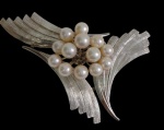 Antigo broche em prata, em formato floral estilizado, ornamentado com pérolas cultivadas, contrastado na parte posterior com marca "Silver". Peso: 17,3 gramas. Medidas: 7 x 4 cm.