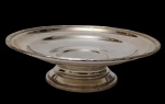 Antiga fruteira / centro de mesa de metal espessurado a prata, elevada sobre base circular, com centro liso e borda delicadamente ornamentada em baixo-relevo por motivos florais e filetes. Medidas: 6 x 22 cm.