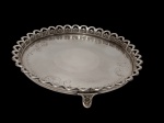 Antiga bandeja redonda em metal espessurado a prata, com borda vazada cinzelado por motivos em concheados, centro liso com delicados elementos gravados e apoiada sobre três pés. Medidas: 4 x 25 cm.