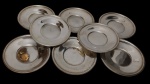 Fracalanza. Conjunto de 8 pratos/ presentoir/pires em metal espessurado a prata, com centro rebaixado e bordas lisas. Medidas: 14,5 cm de diâmetro.