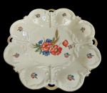 Bavaria. Antigo centro de mesa em porcelana alemã, moldado em relevo com borda recortada e vazada, decorado em policromia com arranjo floral central e pequenos bouquets distribuídos pela aba, com delicados detalhes em ouro. Medidas: 4 x 29 cm.