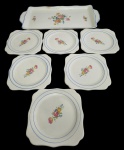 Nadir. Conjunto com 7 peças em faiança esmaltada, decoradas com delicados motivos florais policromados e filetes em azul, composto por 1 travessa retangular com alças e 6 pratinhos. Manufatura no verso. Medidas: pratinhos 2 x 14 cm; travessa 2 x 36 x 18 cm.