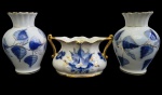 Conjunto com 3 peças em porcelana nacional esmaltada, composto por 2 vasos e 1 floreira, decorados em policromia nas tonalidades de azul e ouro, com motivos florais estilizados e bordas onduladas filetadas a ouro. Manufatura no verso. Medidas: floreira 10 x 17 x 9 cm; vasos 16 x 7 cm.