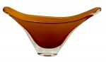 Murano. Antigo vaso artístico de Murano, em tonalidade âmbar com sobreposição translúcida, corpo de linhas orgânicas e bojo em formato de taça aberta, apoiado sobre base maciça em cristal incolor.  Medidas: 23 x 39 x 9 cm.