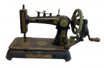 Pavema. Antiga máquina de costura de mesa em miniatura manual em ferro fundido, com decoração em policromia dourada e manivela lateral. Base retangular ornamentada e estrutura original da manufatura. Não funciona. Medidas: 37 x 27 x 20 cm.