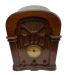 Radio Shack - Rádio de mesa retrô, modelo 12-697A, com gabinete em madeira, receptor AM/FM, mostrador circular central, grade frontal revestida em tecido e plaqueta frontal da marca "Quality Since 1921". Peça de fabricação contemporânea inspirada nos rádios norte-americanos da década de 1930. Medidas: 35 x 28 x 23 cm.