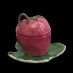 WEISS - Açucareiro em formato de morango, confeccionado em faiança esmaltada e policromada, pintado à mão, com tampa integrada ao fruto e prato em formato de folha. Manufatura marcada na base. Medidas: 13 x 17 x 12 cm.