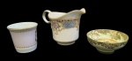 Lote contendo três peças avulsas em porcelana fina, sendo Paragon Fine Bone China England (tigela decorativa), Erskine Heathcote China - England (caneca) e Vizavi Fine Porzellan (cremeira). Peças esmaltadas, decoradas com motivos florais e detalhes dourados. Medidas: 3 x 8 cm; 6 x 6 cm; 9 x 14 x 8 cm.