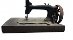 Antiga máquina de costura mecânica com corpo em ferro fundido preto, fixada sobre base retangular original em madeira escura, ideal para uso estritamente decorativo ou cenográfico. Medidas: 40 x 24 x 20 cm.