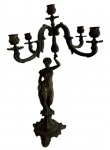 Antigo candelabro decorativo em metal fundido com pátina, apresentando fuste central esculpido em formato de figura feminina clássica em estilo cariátide que sustenta a ramagem superior com cinco braços ornamentados com volutas para velas. Medindo: 50 x 28 x 26 cm. Apresenta desgastes.