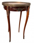 Antiga mesa lateral / mesa de apoio redonda em madeira  estilo Luís XV, apresenta tampo emoldurado por galeria vazada em metal, saia com apliques centrais e pernas esguias no formato cabriolet (curvadas) com sapatas e ponteiras em bronze. Um pequeno desgaste natural na folheação da superfície. Medidas: 74,5 X 49 cm.