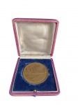 Medalha comemorativa da Constituição do Estado do Rio de Janeiro, datada de 23 de julho de 1975, em metal dourado, apresentando em uma face a representação cartográfica do Estado do Rio de Janeiro e, na outra, vista estilizada da Ponte RioNiterói. Acompanha estojo de apresentação original. Medidas: 6,5 cm de diâmetro.