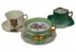 Três xícaras de coleção para café em porcelana, de modelos distintos, com decorações florais, heráldicas e acabamento esmaltado, com detalhes em douração.
