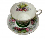 Royal Albert, Inglaterra. Antiga xícara de chá com pires em fina porcelana inglesa  apresentando elegante formato gomado com bordas lobadas e frisos pintados a ouro, ricamente decorada externamente e no fundo interno com policromia de arranjos florais, rosas e composições de frutas. Manufatura no verso.