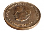 Antiga medalha comemorativa em metal patinado, dedicada ao educador e radioeducador Roquette-Pinto, com efígie em relevo no anverso e inscrição no reverso: "Pela cultura dos que vivem em nossa terra, pelo progresso do Brasil", datada de 1981. Acompanha estojo de apresentação original. Medidas: 7 cm de diâmetro.