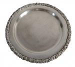Sheffield  Bandeja redonda em metal espessurado a prata, marcada na base. Centro finamente gravado por arabescos e borda ricamente ornamentada em relevo com motivos florais e concheados. Medidas: 34,5 cm de diâmetro.