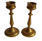 Antigo par de castiçais em bronze, com fuste torneado e base circular escalonada. Medidas: 18,2 x 8,8 cm.