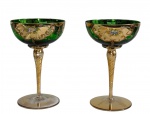 Antigo par de imponentes taças em cristal veneziano, na cor verde translúcido, com hastes torcidas e bojo ricamente ornamentado com reservas douradas, arabescos e delicada decoração floral policromada, executada à mão. Medidas: 17,5 x 11,2 cm.