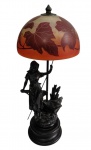 Ravagnani - Imponente abajur / luminária de mesa de estilo Art Nouveau, com escultura em petit bronze representando figura feminina sobre base em madeira torneada, sustentando cúpula em vidro artístico acetinado, decorada com folhas e flores em tons de âmbar e vinho. Peça assinada, em funcionamento. Medidas: 60 cm de altura.