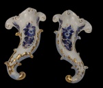 Par de antigas floreiras de parede em porcelana, ricamente moldadas em relevo, com decoração floral em policromia nos tons de azul e detalhes filetados a ouro. Marcadas no verso. Medidas: 24 x 14 cm cada.