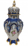 Santa Terezinha Pedreira - Antigo potiche em porcelana esmaltada, com tampa, ricamente moldado em relevo, decorado em azul-cobalto, reservas florais em policromia e detalhes filetados a ouro. Marcado na base. Medidas: 34 x 15 cm.