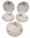 C.T. Poland - Sete pratos rasos em porcelana polonesa esmaltada, com decoração floral policromada, bordas recortadas e filetadas a ouro. Marcadas na base. Medidas: 25 cm. Um com fio de cabelo.