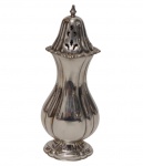 Inglaterra. Antigo e imponente polvilhador em metal espessurado a prata, com tampa removível perfurada, ornamentada por recortes vazados e arrematada por pináculo. Base moldurada com decoração em relevo. Manufatura na base. Medidas: 18 x 6 x 4,5 cm.